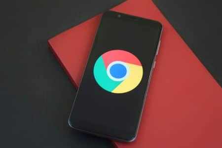 Ces innovations de Chrome sur iOS offrent une expérience révolutionnaire qui va redéfinir votre navigation Close-up of a smartphone with Chrome browser logo on screen placed on a red notebook.