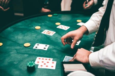 Casinos en ligne : ces critères essentiels pour choisir un site fiable en toute sécurité et légalité Casino scene with dealer and players, featuring cards and chips, creating a suspenseful atmosphere.