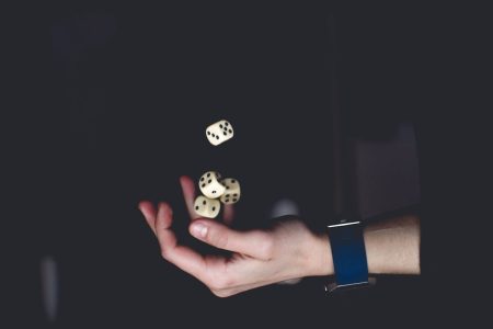 Choisir un site de paris sportifs en 2025 : conseils et critères pour une expérience sécurisée A close-up of a hand tossing several dice against a dark background, symbolizing chance and luck.