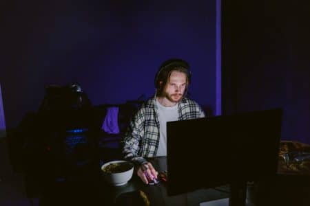 Le jeu de niveau supérieur : comment les retours des fans stimulent les plus grandes innovations du jeu vidéo A focused man playing video games on a computer at night with a headset.