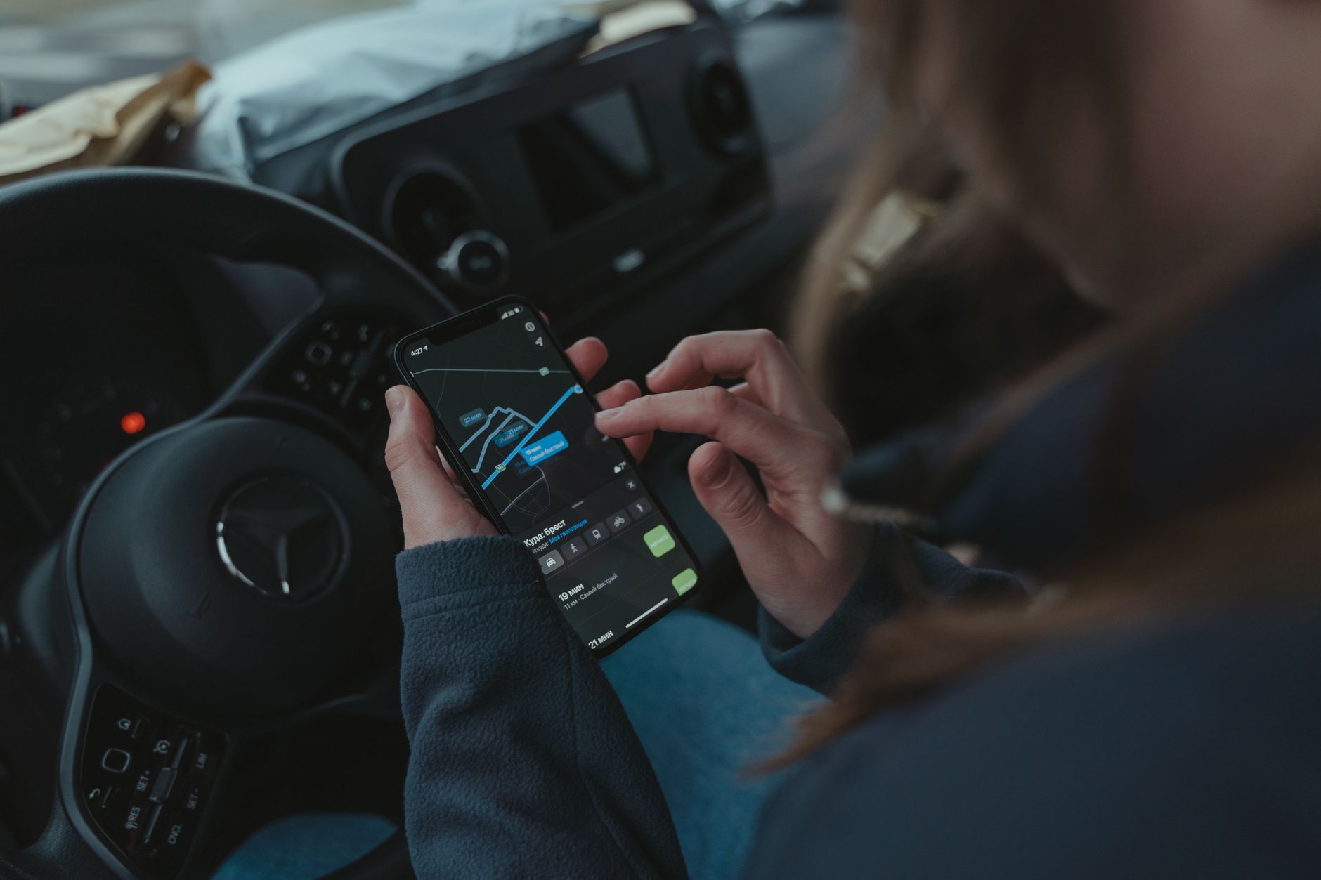 Personne utilisant une application de navigation GPS sur smartphone dans une voiture pour obtenir des indications.