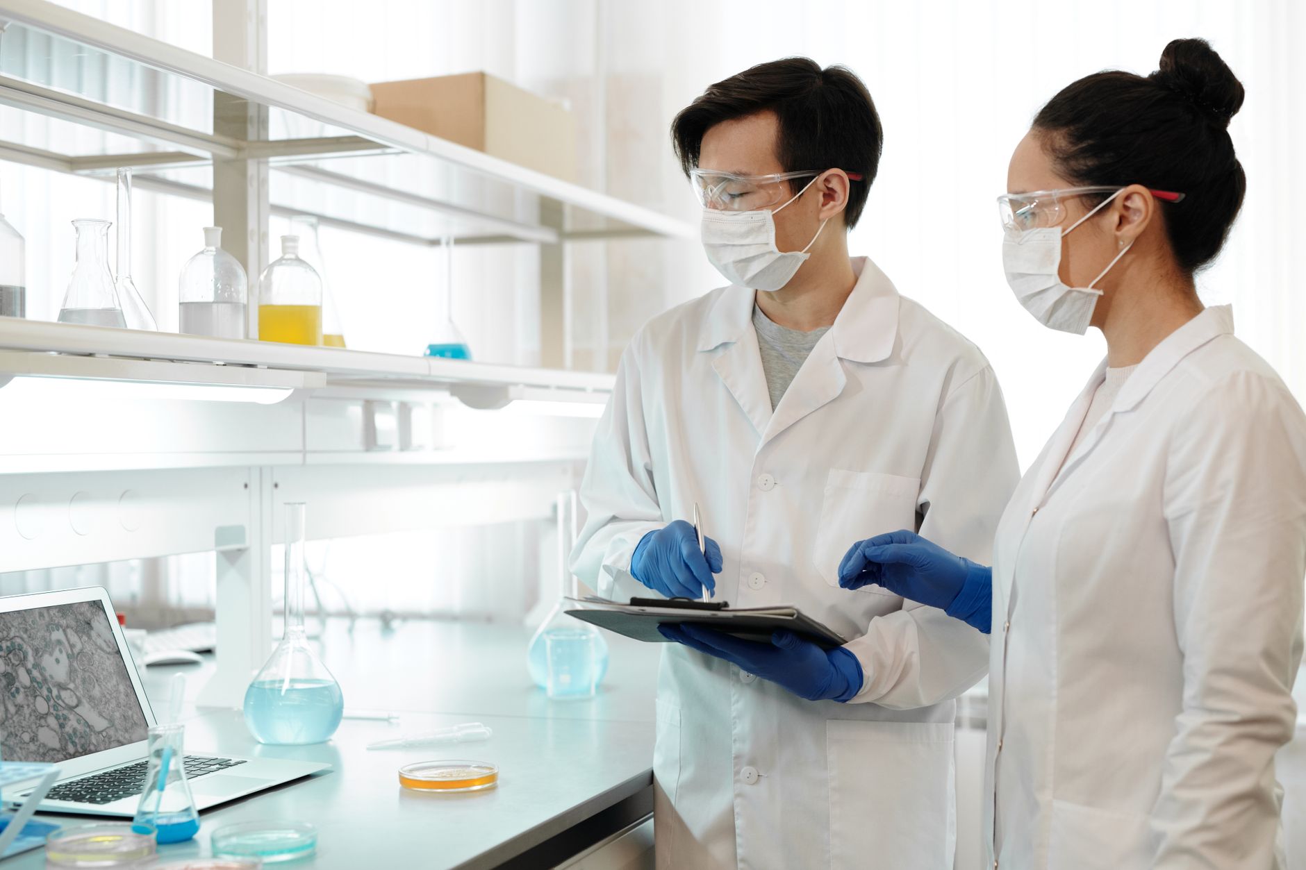 Chercheurs en laboratoire portant masques, gants et lunettes de protection travaillant sur des expériences scientifiques.