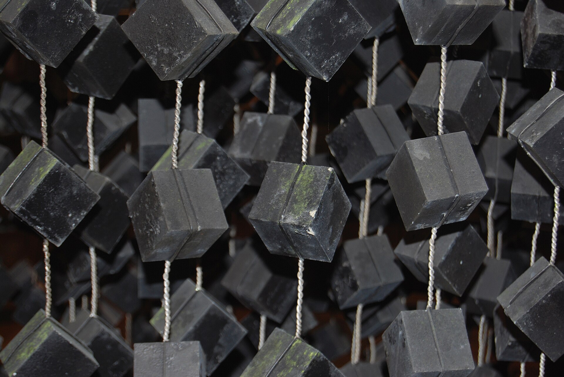 Cubes d’uranium noirs suspendus à des fils dans une reconstitution du réacteur de Heisenberg